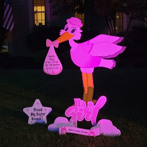 Stork lawn sign lit up in pink